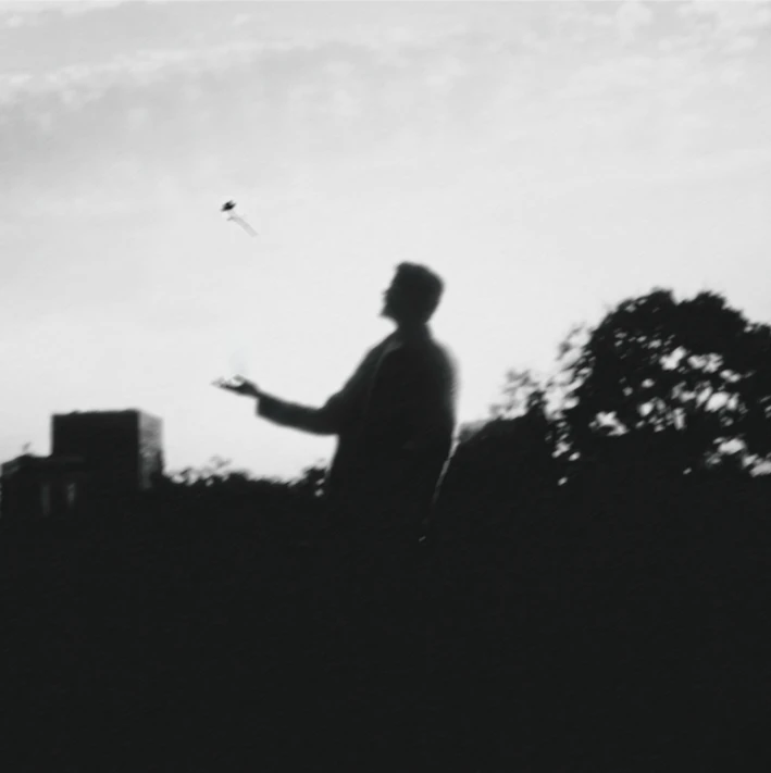 Pochette de Praeter : en noir et blanc, une silhouette lance un objet vers le ciel au crépuscule