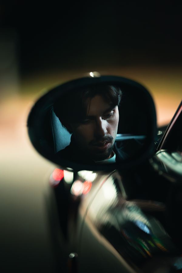 Le visage de Langa dans le rétroviseur extérieur d’une voiture, la nuit