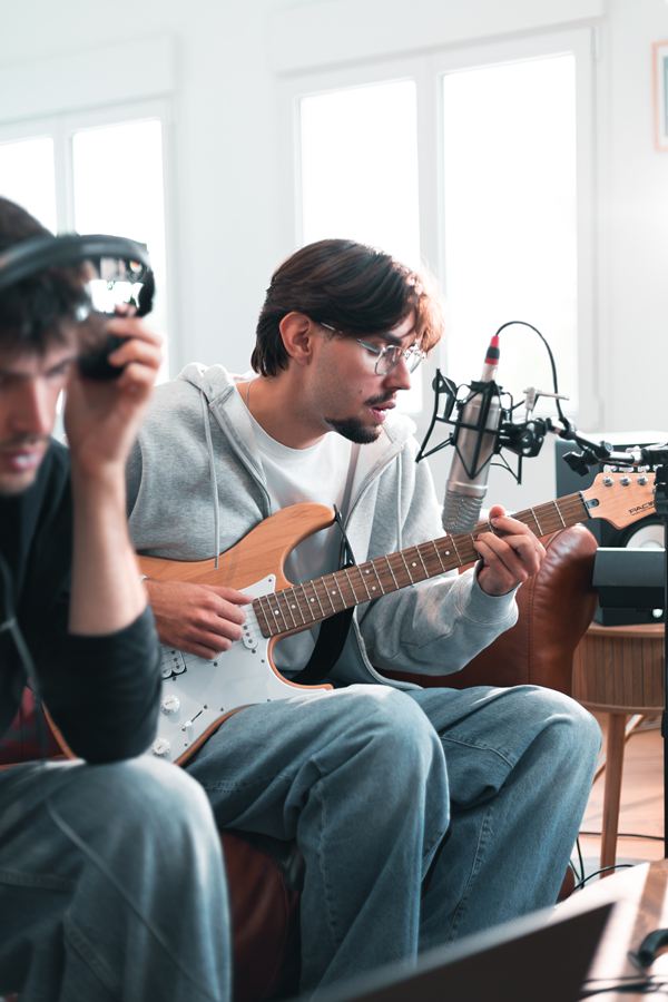 Langa à la guitare et au micro, un musicien au casque au premier plan