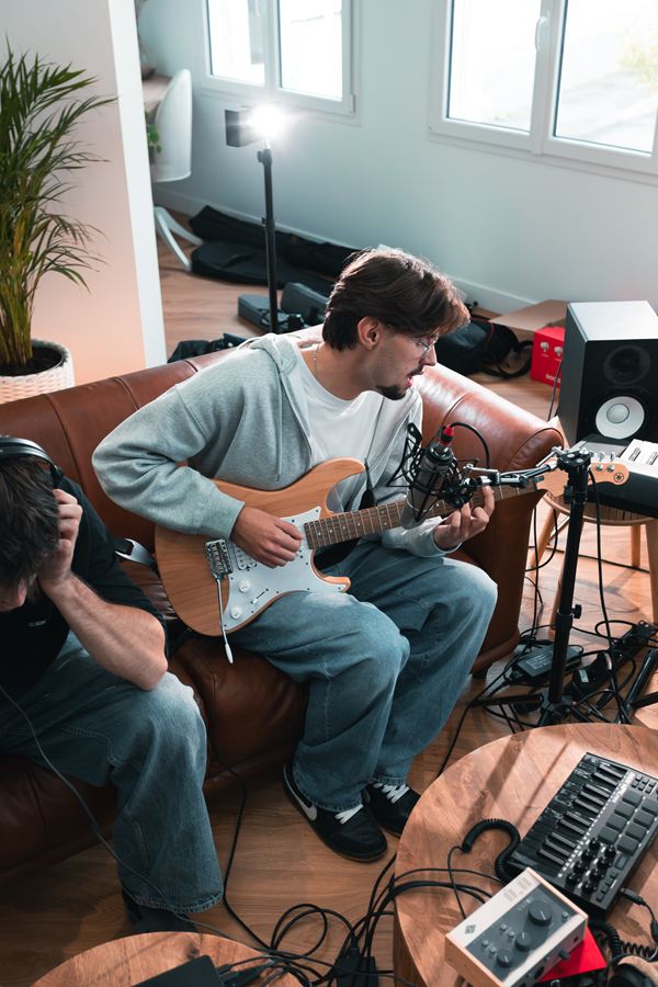Vue plongeante sur Langa à la guitare et au micro, un musicien au casque à côté de lui