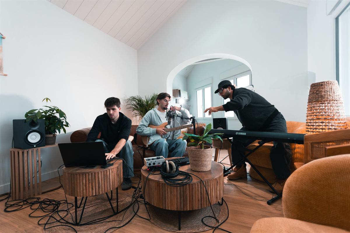 Session dans un salon transformé en studio : Langa à la guitare et au micro, entouré de deux musiciens à l’ordinateur et au clavier